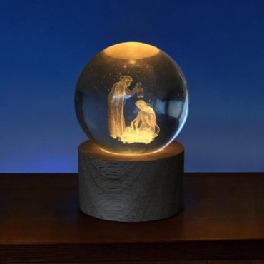 Boule sur socle en bois avec nativité gravée au laser et lumière LED. Hauteur 9 cm..