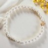 Bracelet sur élastique imitation nacre Ø 5 mm croix laiton doré.