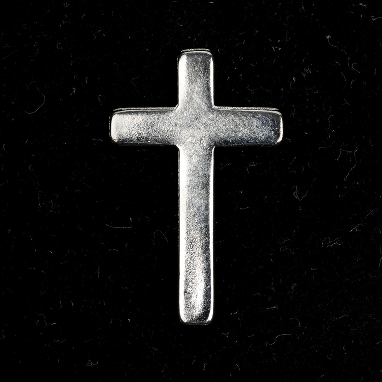 Pin´s croix en métal couleur argentée H. 2,5 cm.